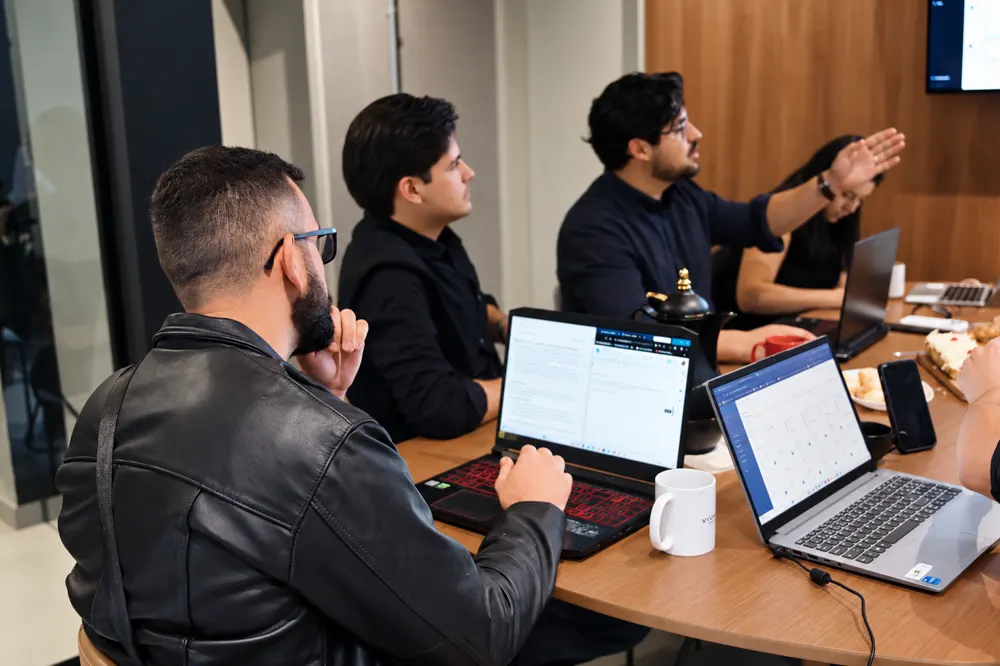Equipe da Outlier Digital em reunião com notebooks abertos